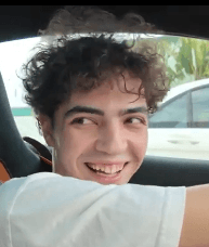Ethan Prosper smiling in a car, with curly brown hair